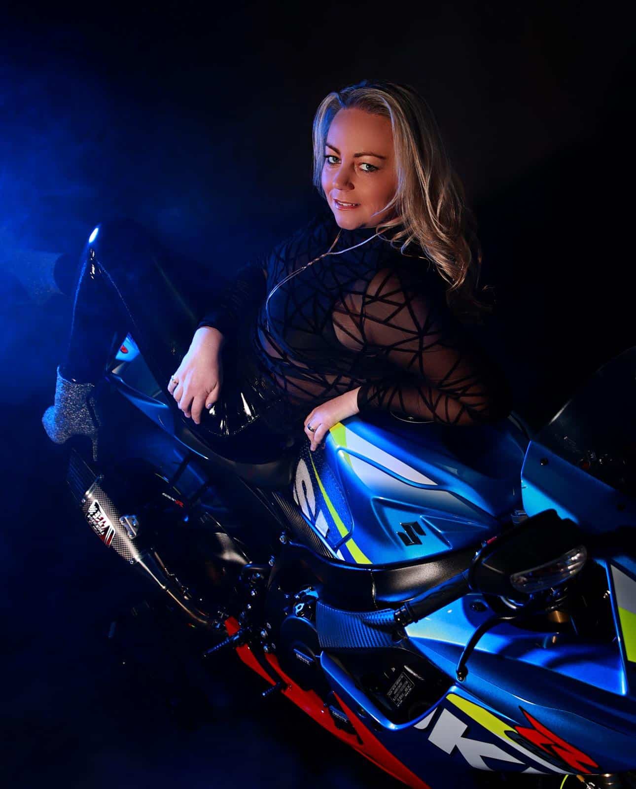 Studio portrait of a woman sitting beside a motorcycle